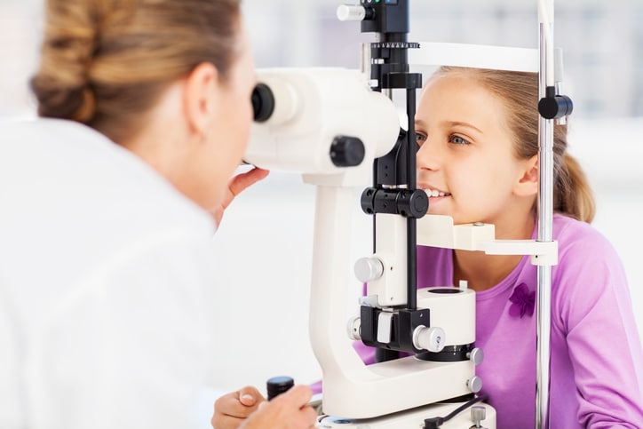 Girl undergoing eye examination in clinic. Horizontal shot.
