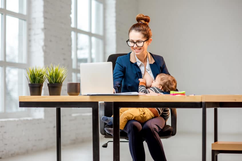 Woman breastfeeding her baby while working at the office
